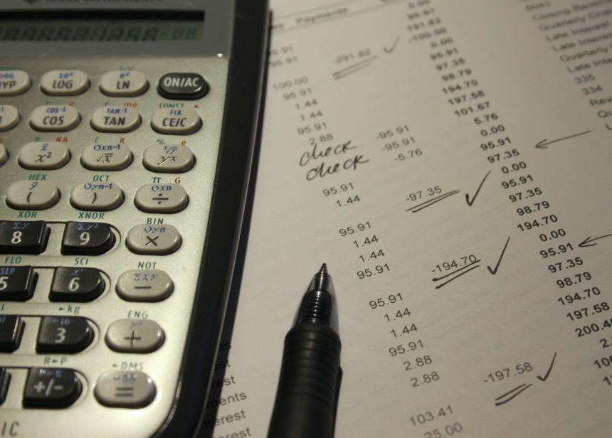 Calculator and uncapped pen on top of paper aging